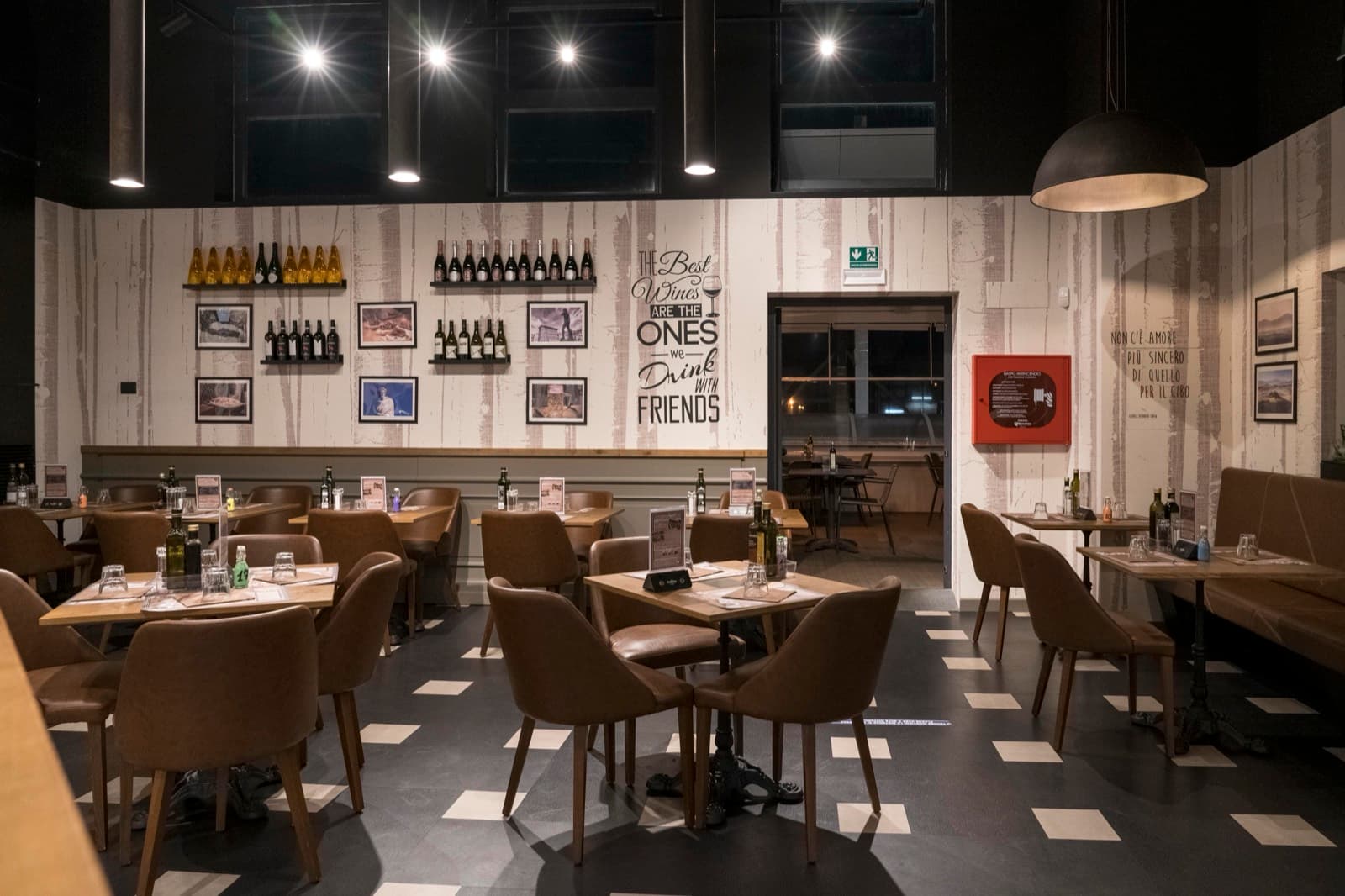 La sala di DaSaba – I Gigli: tavoli in legno, poltroncine in pelle e parete di vini